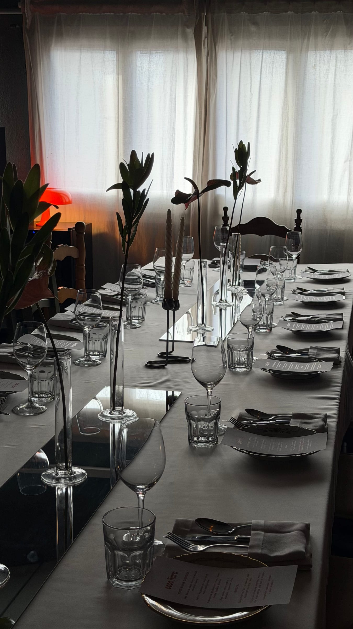 Mesa larga con copas y jarrones en una sala blanca