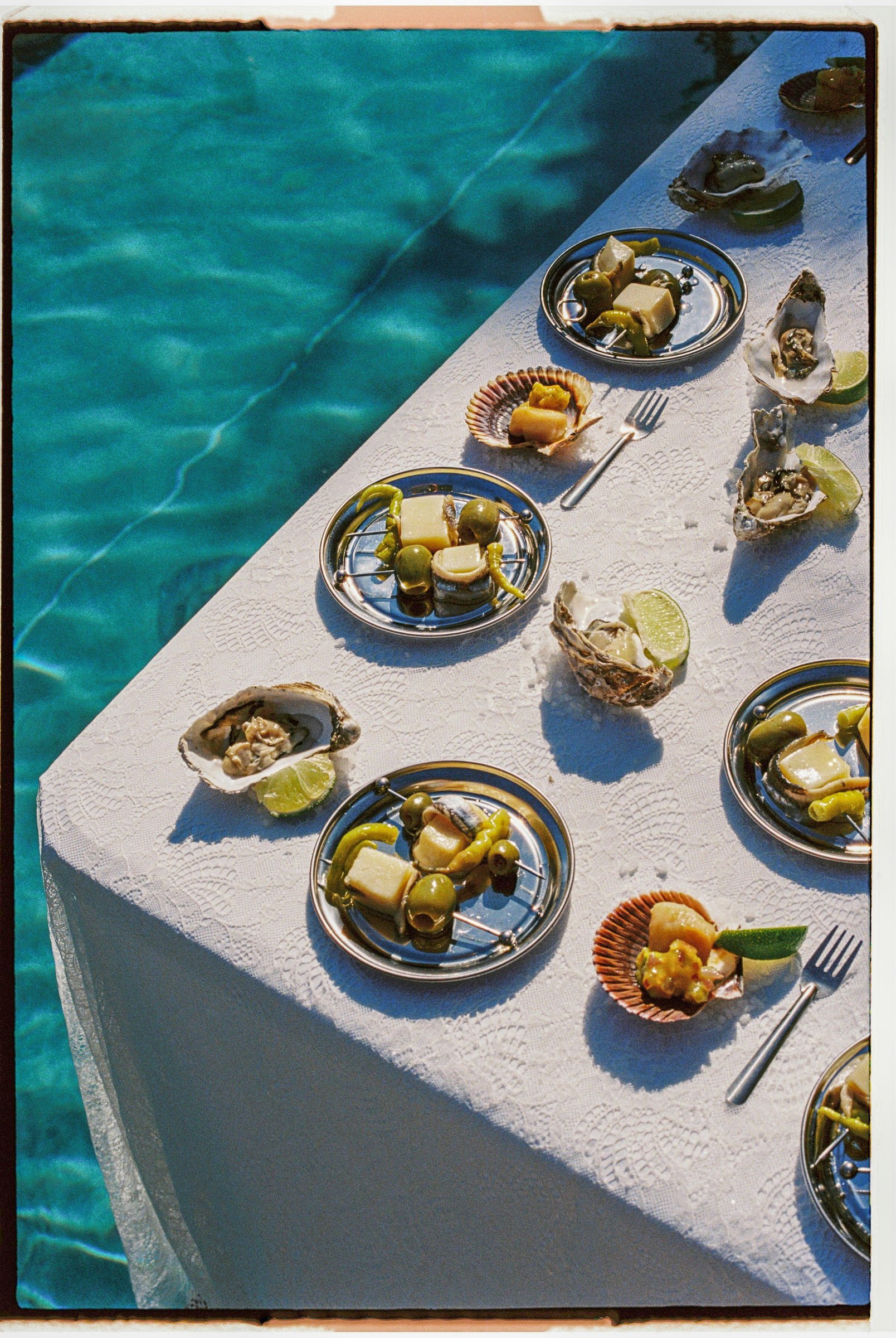 Mesa con platos de ostras junto a una piscina