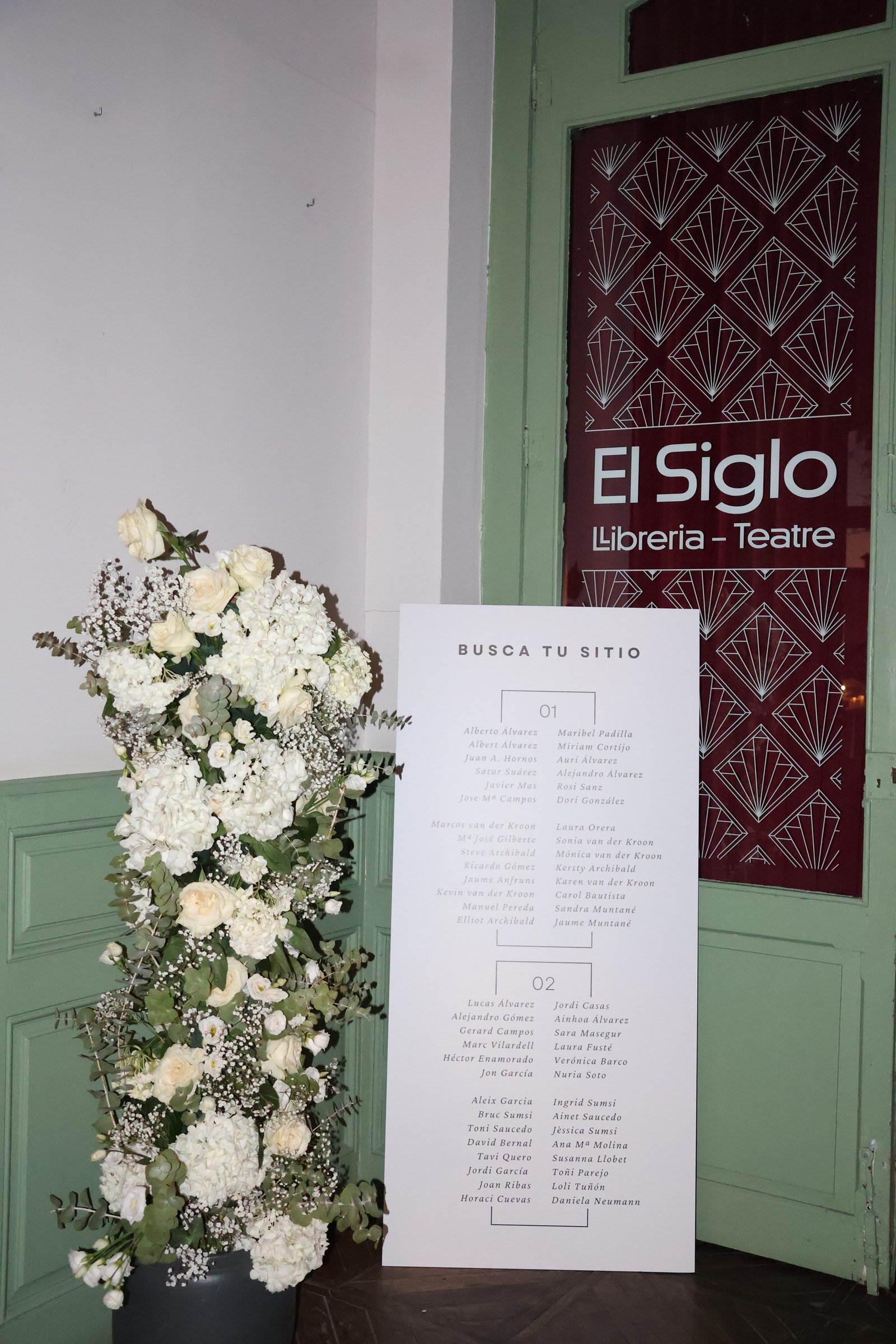 Flores blancas y el plano de mesas a la entrada de El Siglo