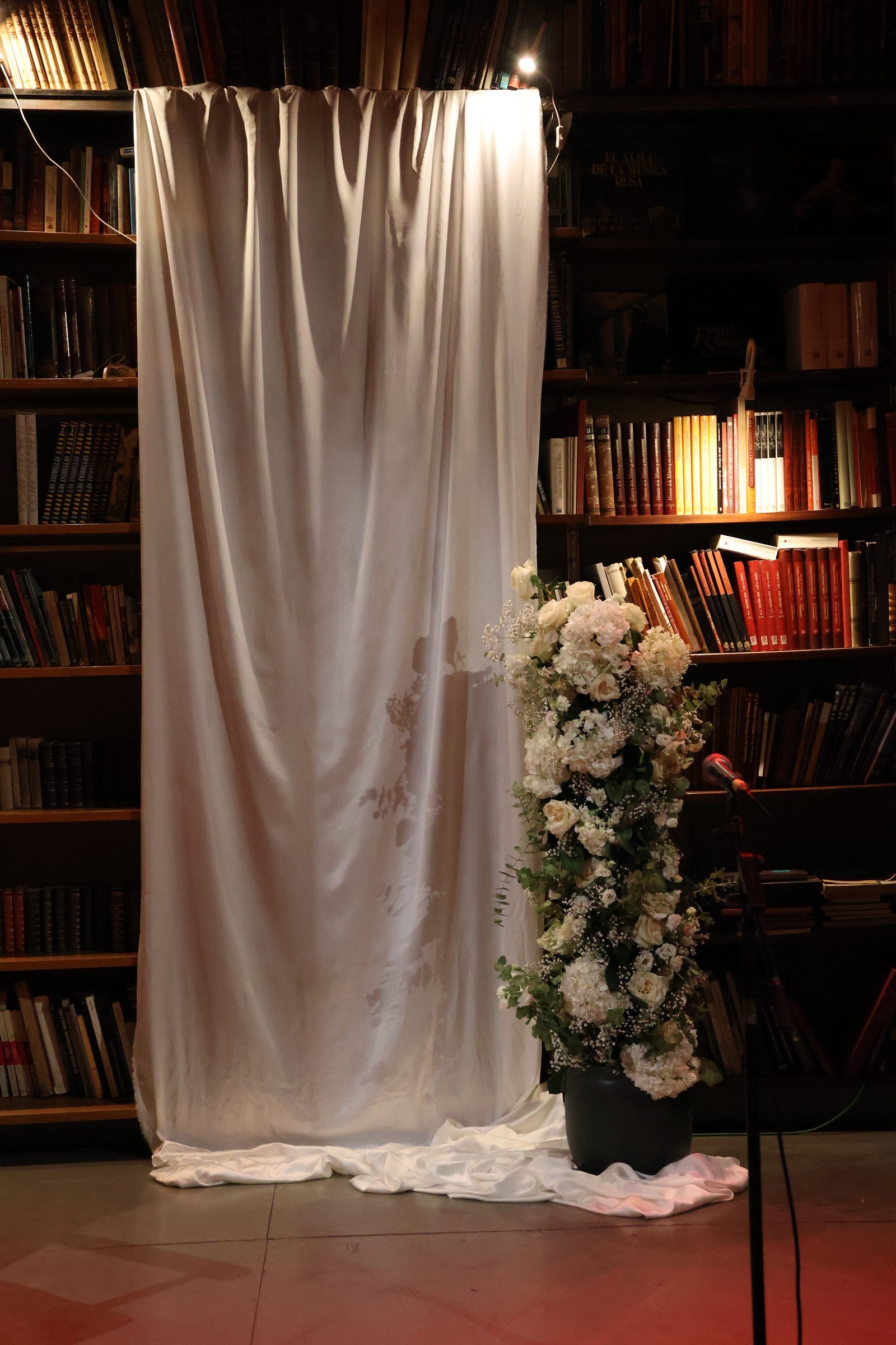 Librería con una cortina blanca y flores al pie