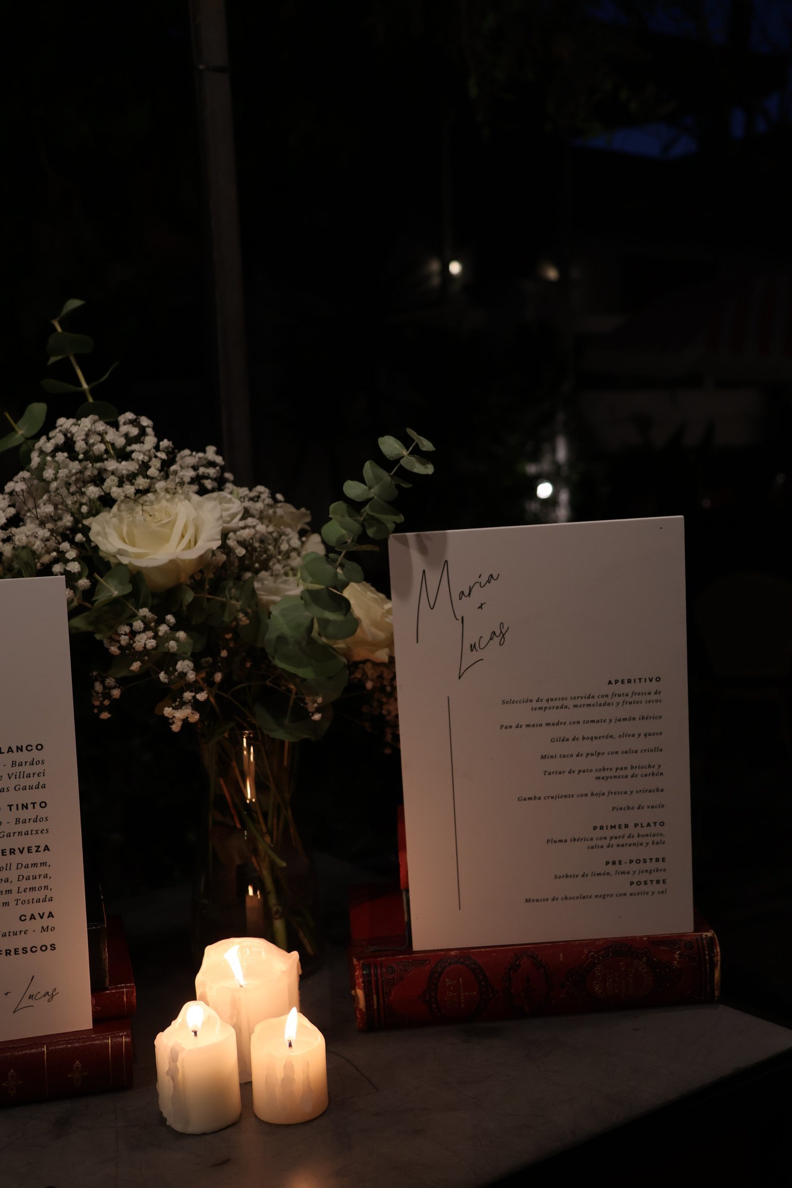 Menú y flores blancas junto a velas encendidas