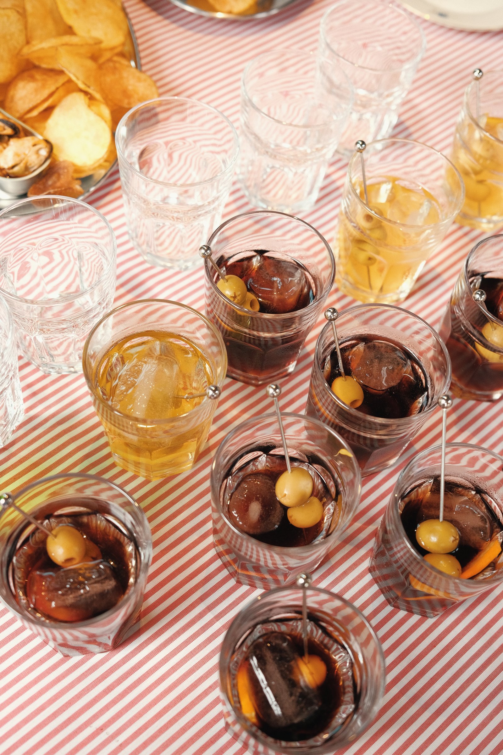 Vasos de vermut con aceitunas sobre un mantel de rayas