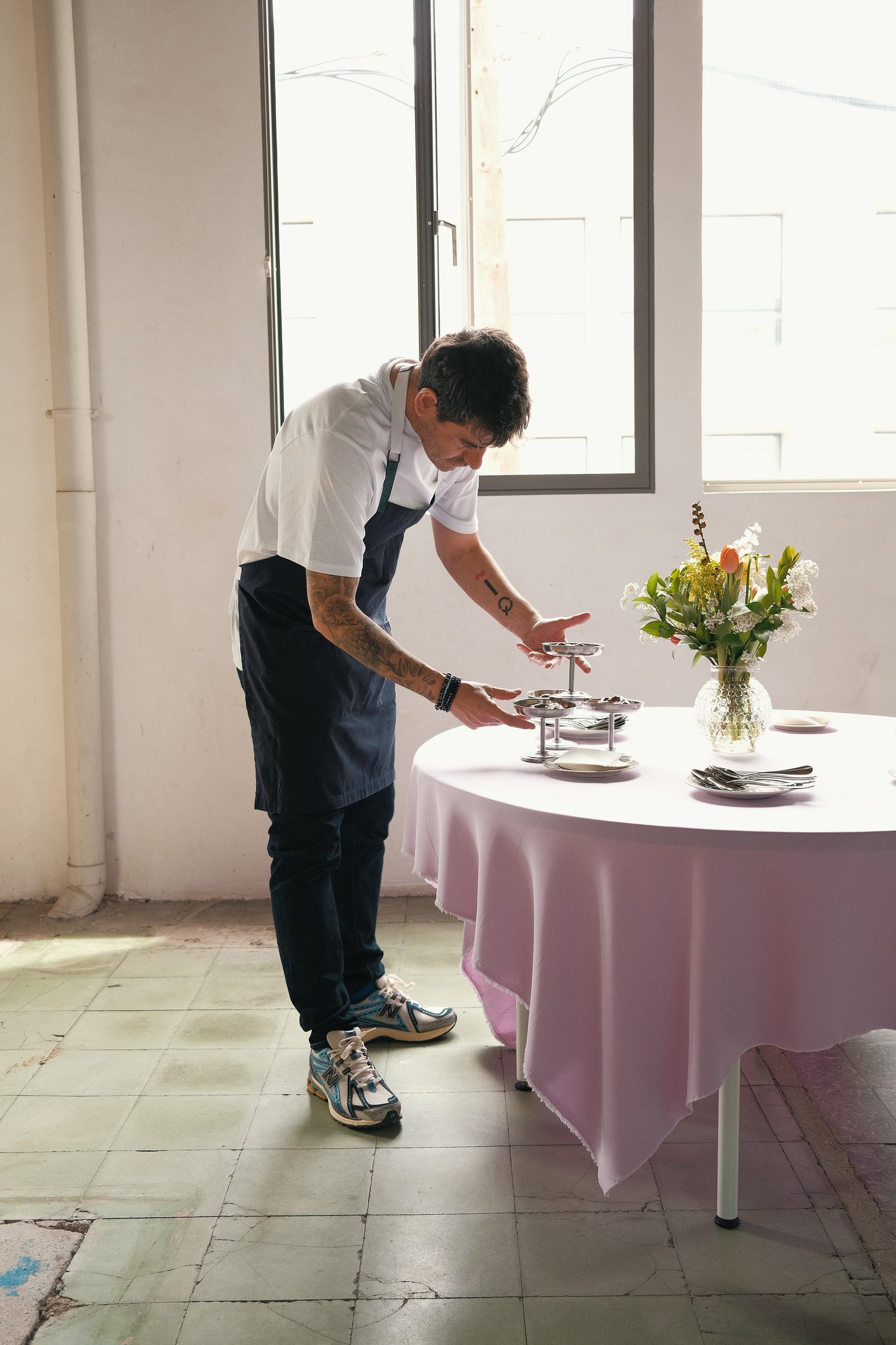 Cocinero preparando una mesa redonda con mantel rosa