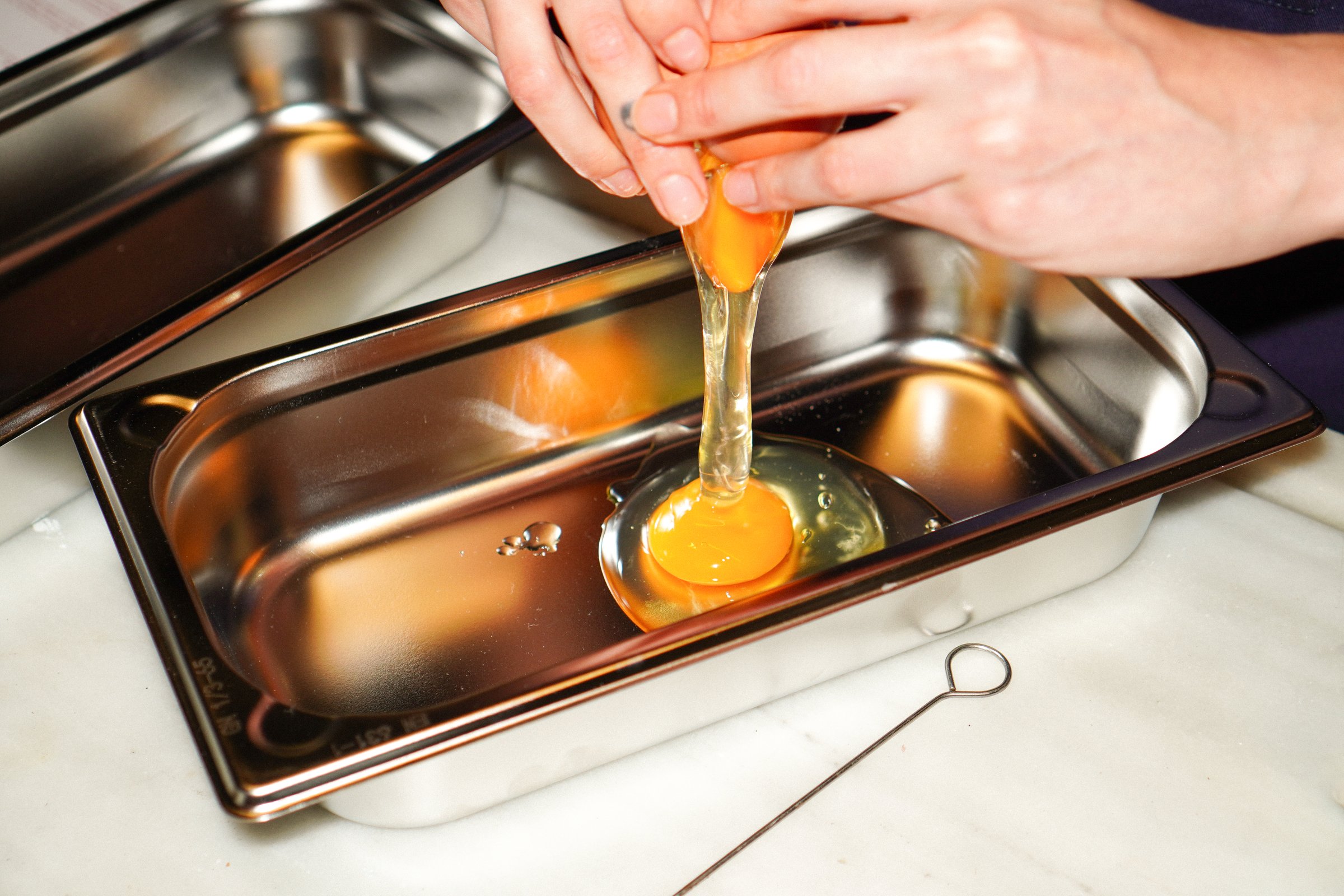 Separando la yema de un huevo sobre una bandeja de acero