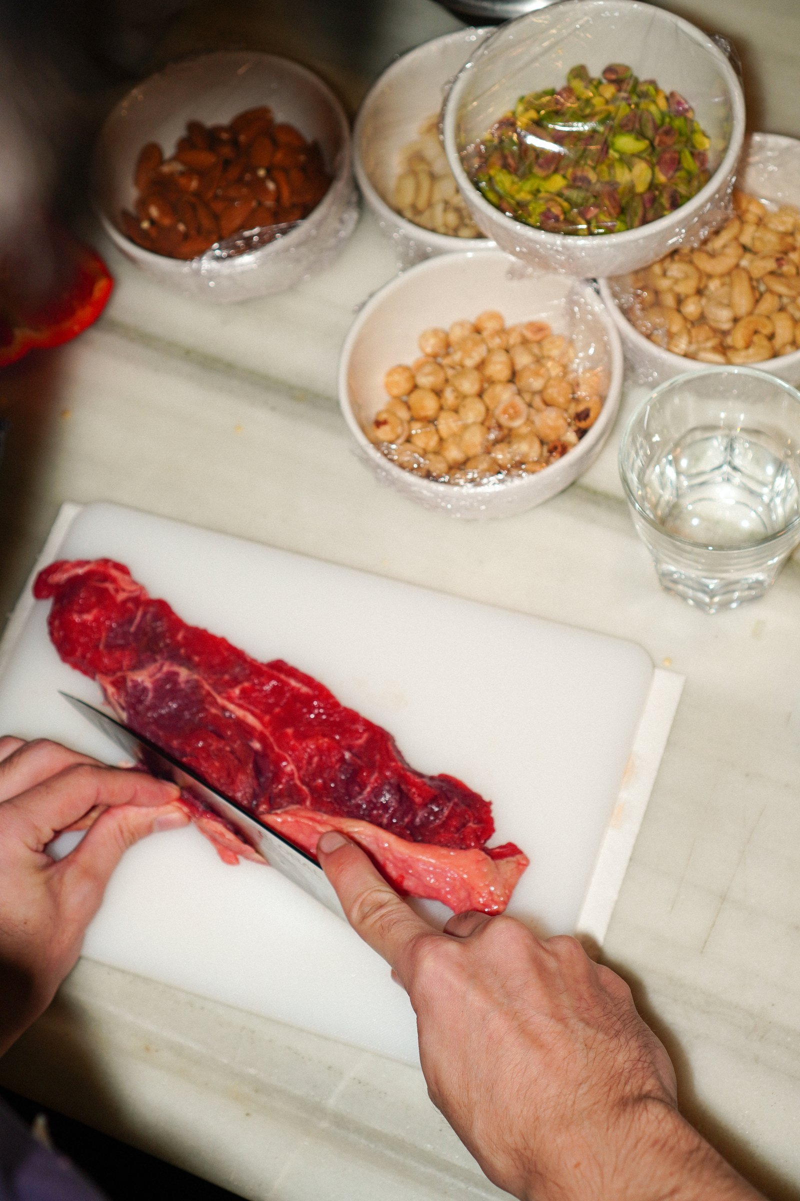 Cortando carne junto a boles de frutos secos y garbanzos
