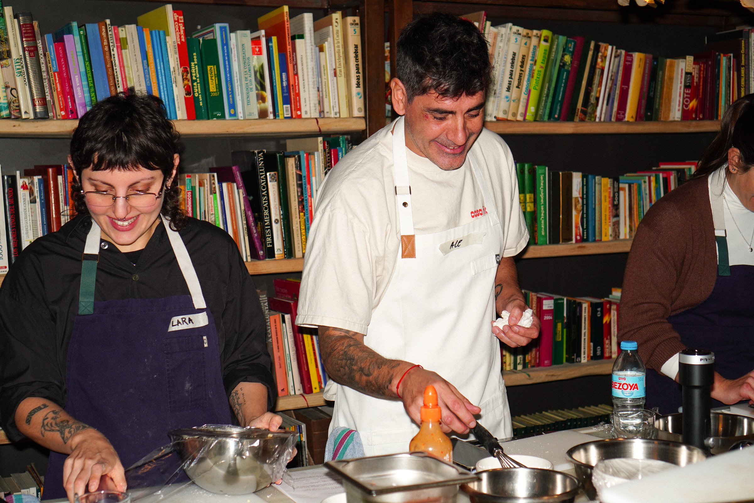 El chef cocinando junto a los participantes ante una estantería de libros